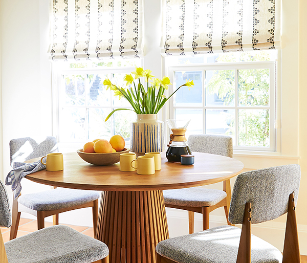 Kitchen nook with vibrant yellow color, mid-century modern chairs and patterned roman shades